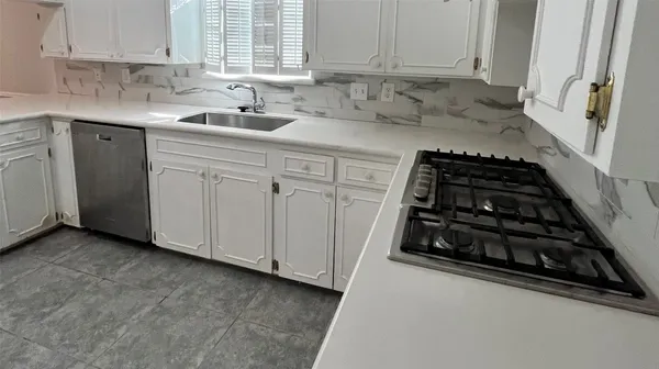 a kitchen with white cabinets and a stove a sink