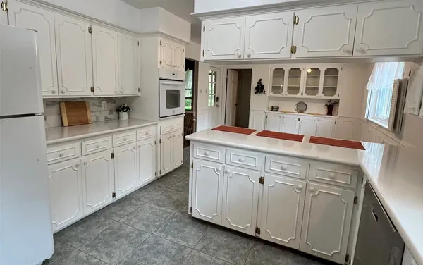 a kitchen with stainless steel appliances granite countertop white cabinets and a refrigerator