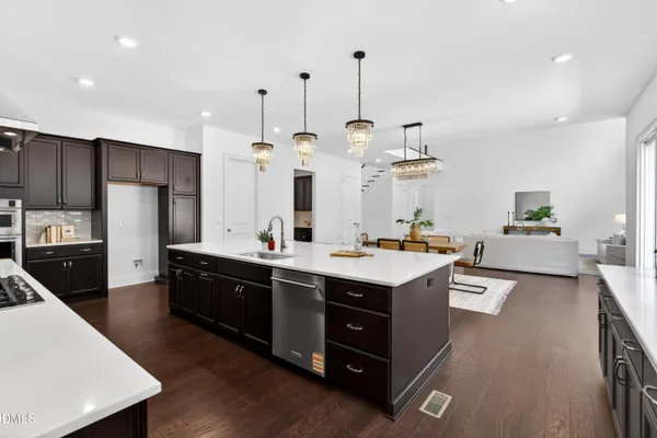 a kitchen with stainless steel appliances kitchen island granite countertop a sink a stove and a wooden floors