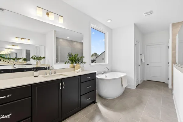 a bathroom with a tub a sink a mirror and a shower
