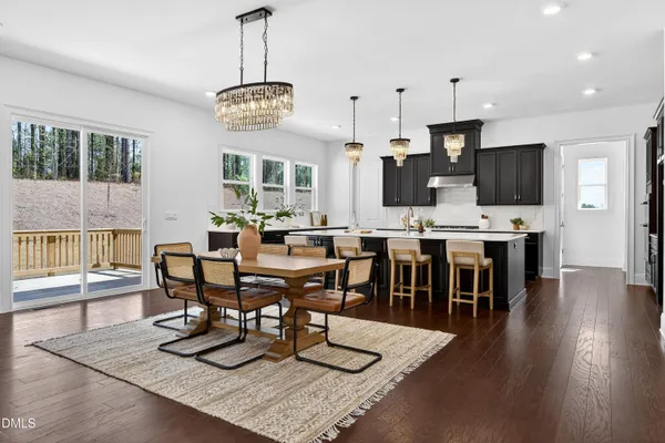 a dining room with wooden floor a chandelier a wooden table and chairs