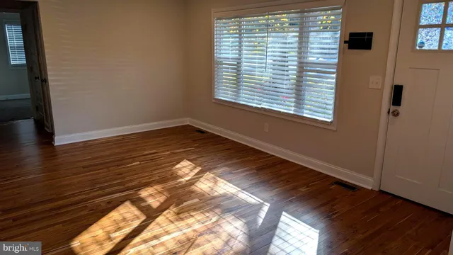 a view of an empty room with wooden floor and a window