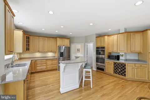 a large kitchen with stainless steel appliances kitchen island granite countertop a large cabinets and a wooden floor