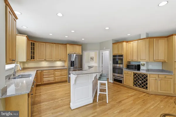 a large kitchen with stainless steel appliances kitchen island granite countertop a large cabinets and a wooden floor