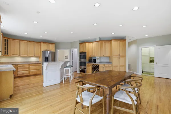 a kitchen with stainless steel appliances kitchen island granite countertop a stove a sink a refrigerator and island with wooden floor