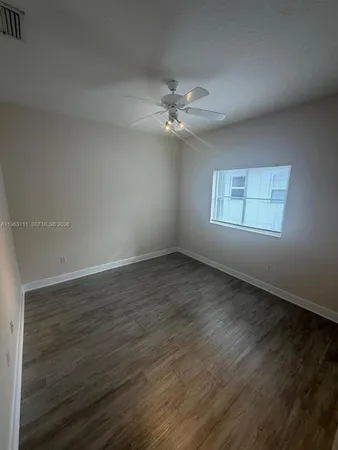 an empty room with wooden floor ceiling fan and windows