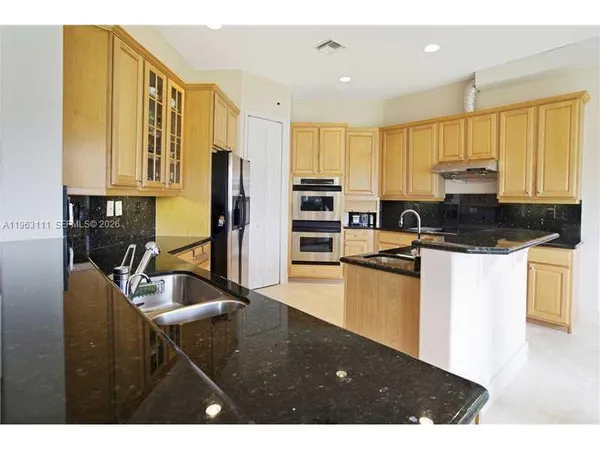 a kitchen with stainless steel appliances granite countertop a stove top oven a sink and a refrigerator