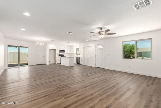a view of an empty room with kitchen and window