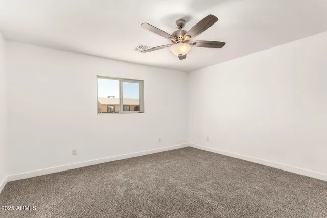 an empty room with a ceiling fan and a window
