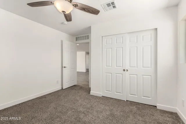an empty room with a window and ceiling fan