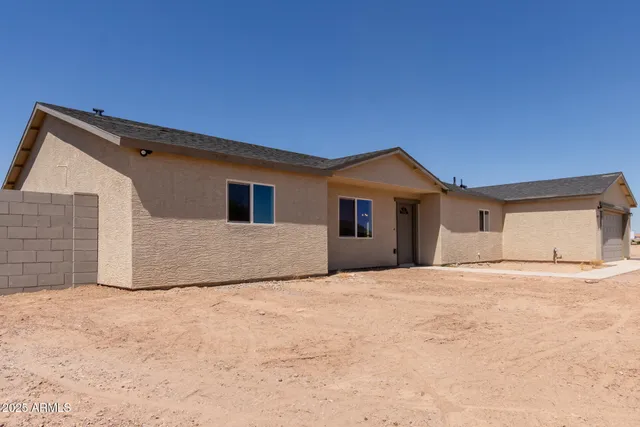 an empty room with wooden floor kitchen view and a ceiling fan