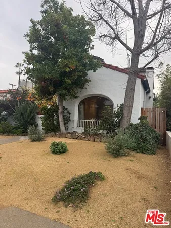 a front view of a house with a yard covered with snow and trees