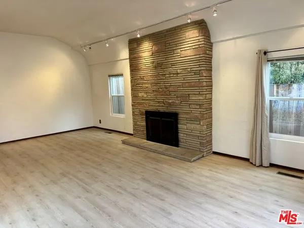 an empty room with wooden floor and fireplace