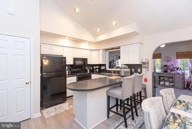 a kitchen with stainless steel appliances granite countertop a refrigerator a stove a sink a dining table and chairs with wooden floor