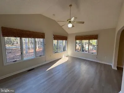 a view of an empty room with wooden floor and a window