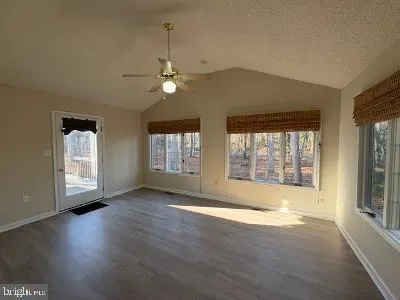 a view of an empty room with a window and wooden floor