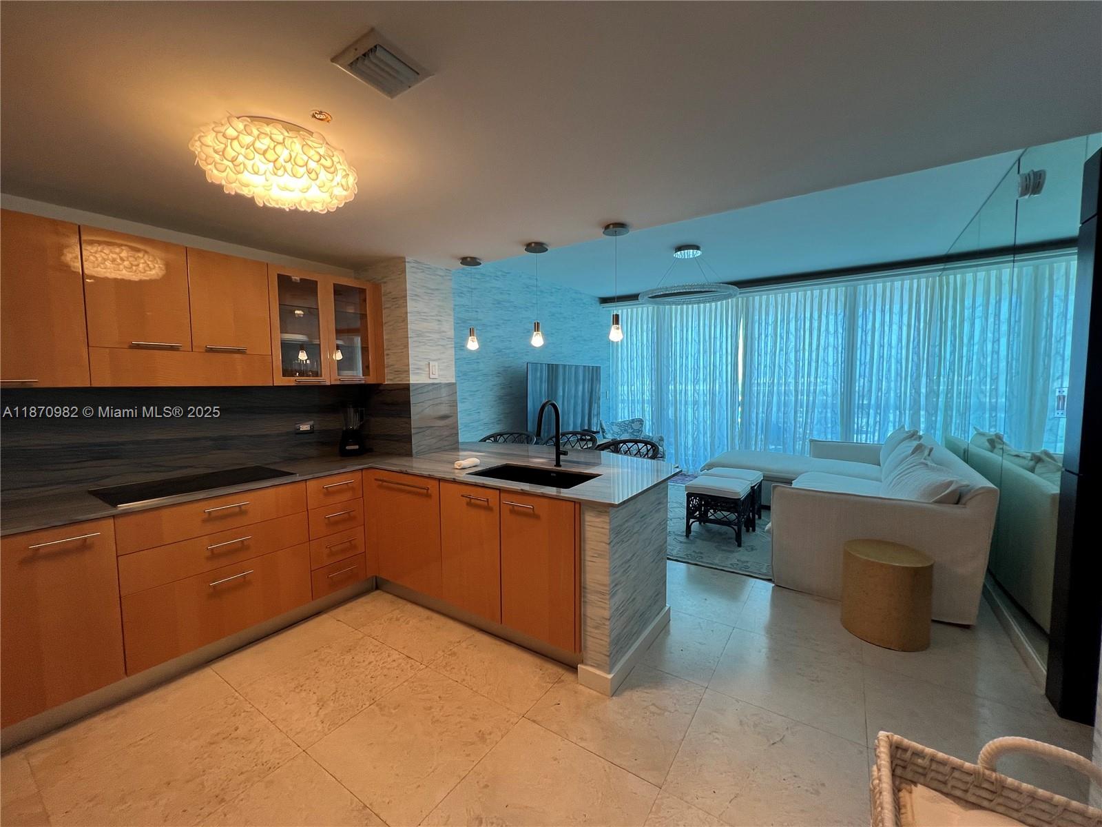 6799 Collins Avenue, Unit 1601 Miami Beach, FL 33141 - Photo 4 of 27 a large kitchen with stainless steel appliances granite countertop a sink dishwasher a stove and a refrigerator with wooden floor