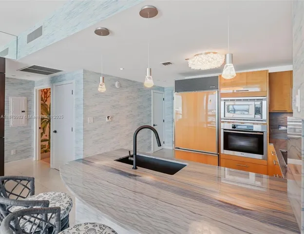 a kitchen with stainless steel appliances granite countertop a stove a refrigerator and a fireplace with wooden floor