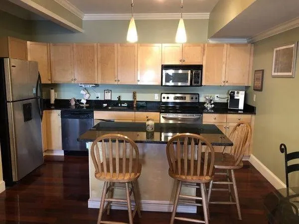 a kitchen with stainless steel appliances granite countertop a dining table chairs refrigerator and sink