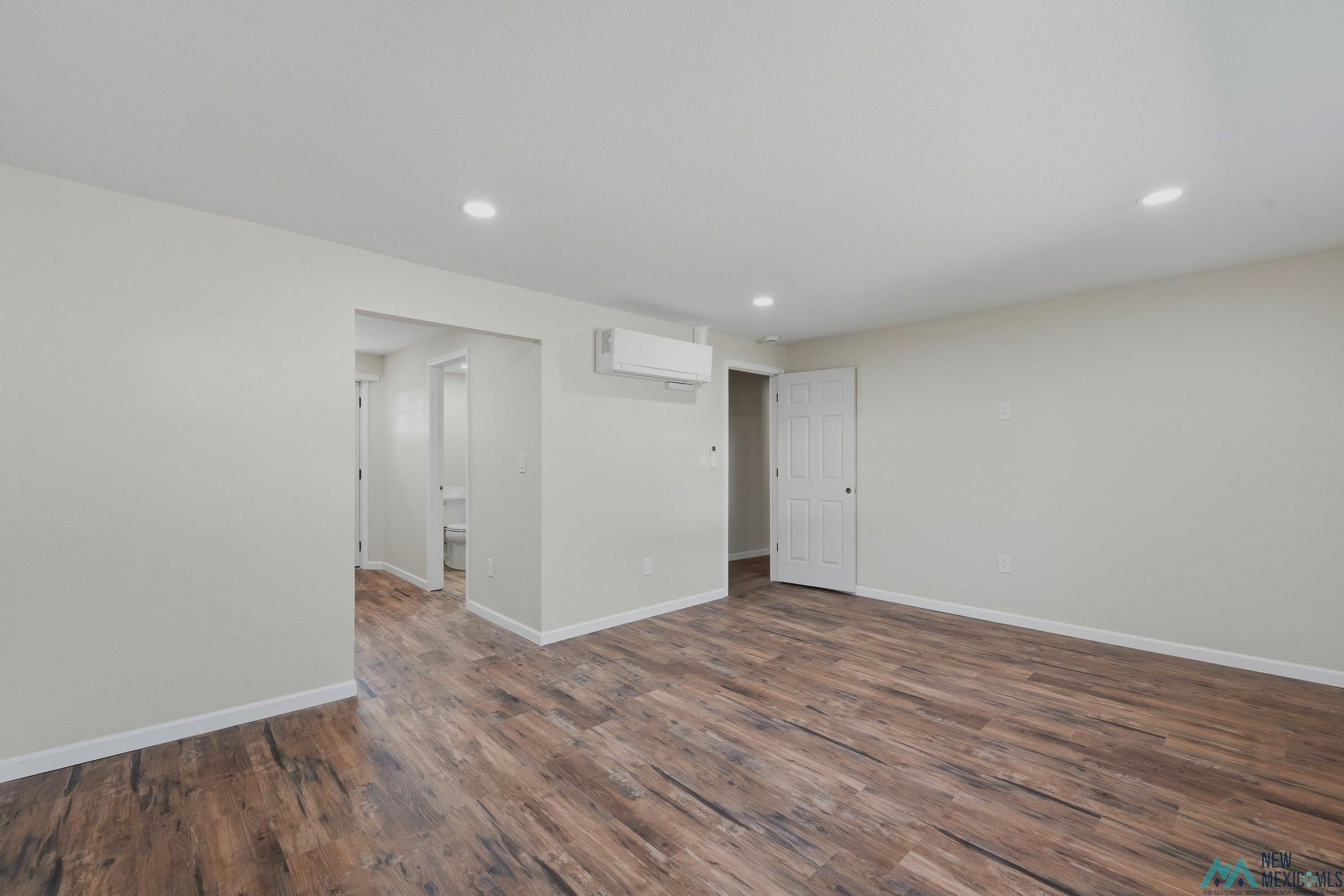 544 South 13th Avenue Raton, NM 87740 - Photo 14 of 37 Spacious room featuring wood-finish flooring, recessed lighting, and a wall-mounted climate control unit
