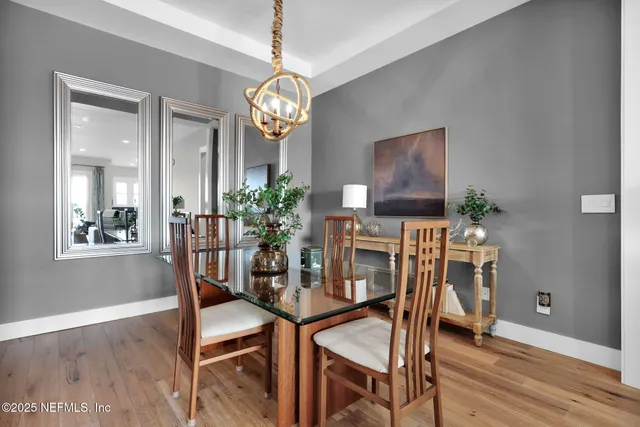 a dining room with furniture a chandelier and wooden floor