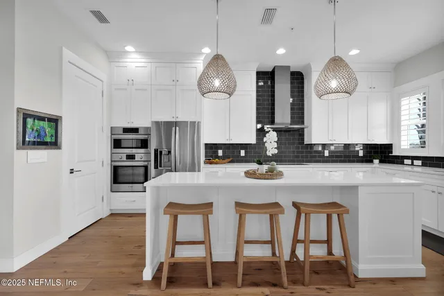 a kitchen with stainless steel appliances granite countertop a stove a refrigerator a oven a sink with a dining table and chairs