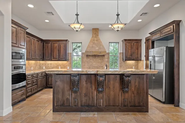 a kitchen with stainless steel appliances granite countertop a stove refrigerator and cabinets