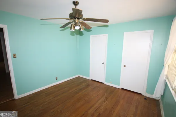 an empty room with a fan and a window