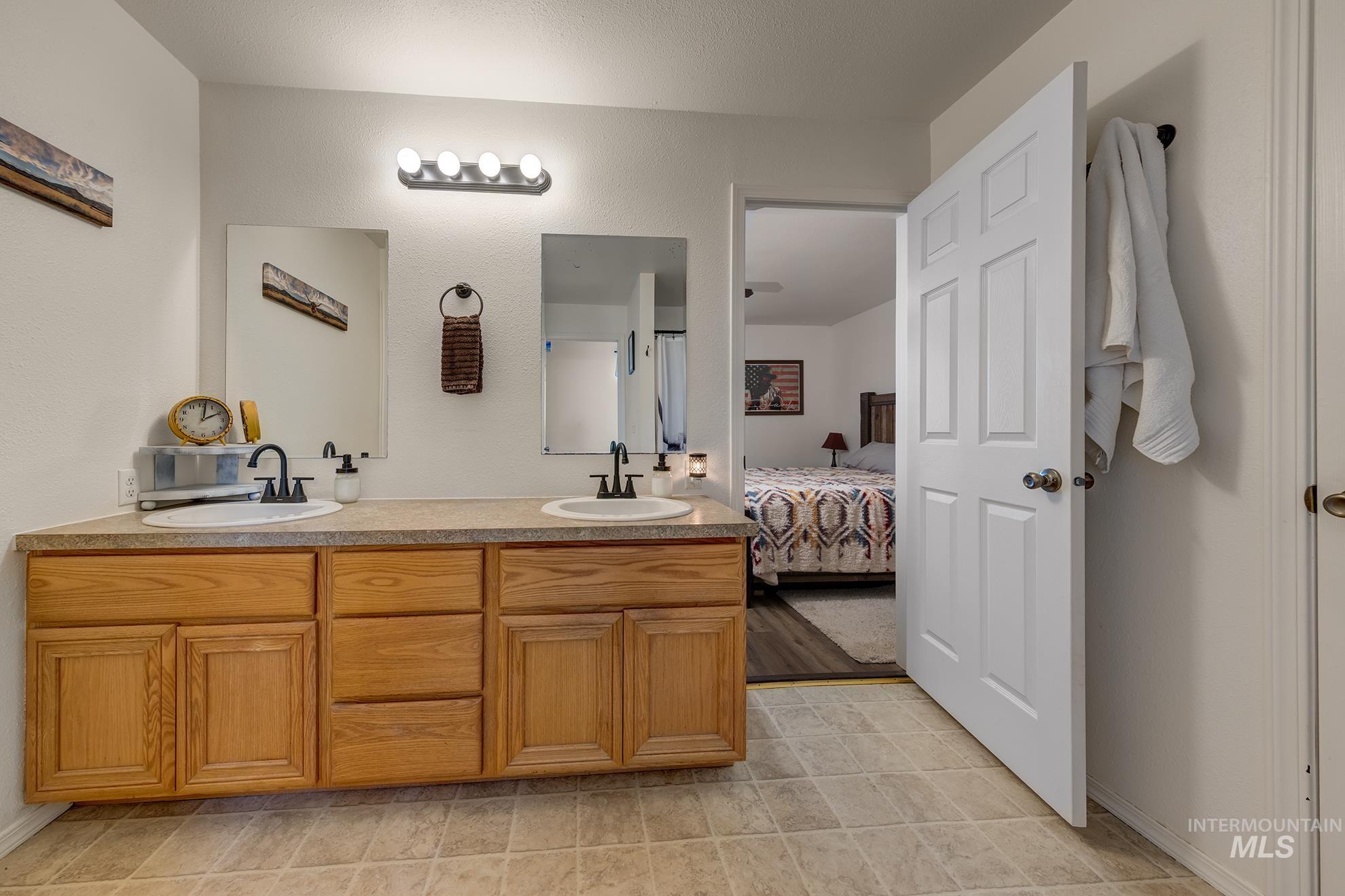 4631 Rolland Road Ontario, OR 97914 - Photo 13 of 43 Dual undermount sinks with matte black fixtures, wood-finish cabinetry, and a light-toned countertop