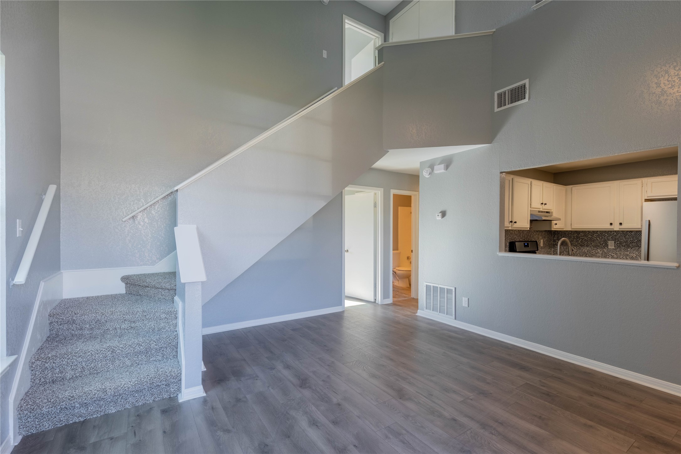 319 Rawhide Loop Round Rock, TX 78681 - Photo 13 of 28 Unfurnished living room featuring dark wood-style flooring, stairs, and a towering ceiling