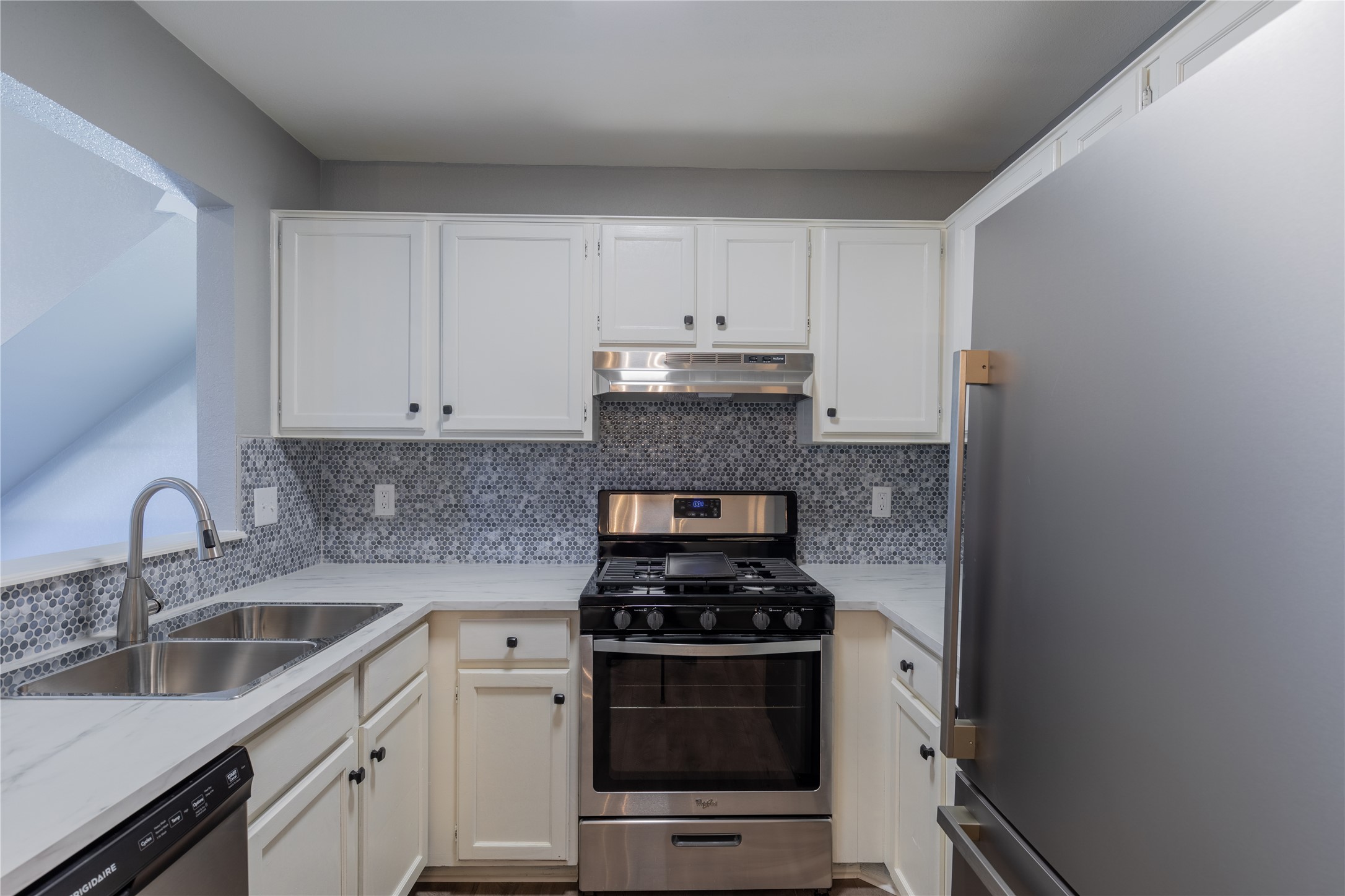 319 Rawhide Loop Round Rock, TX 78681 - Photo 8 of 28 Kitchen with appliances with stainless steel finishes, white cabinets, backsplash, and under cabinet range hood