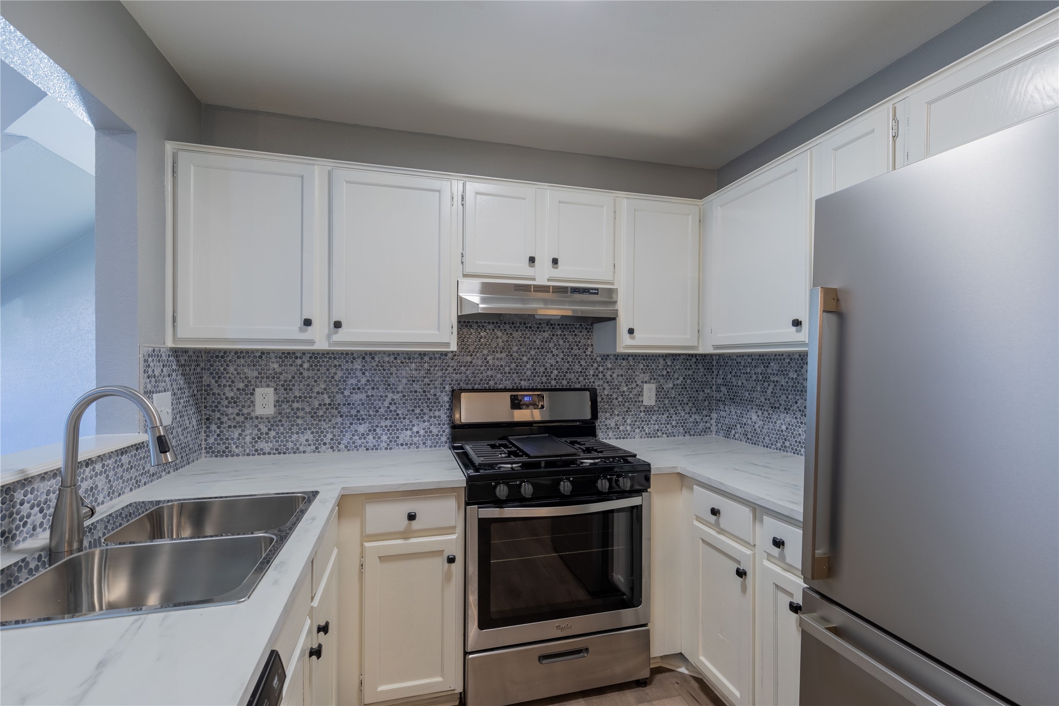 319 Rawhide Loop Round Rock, TX 78681 - Photo 9 of 28 Kitchen with stainless steel appliances, white cabinets, backsplash, and under cabinet range hood