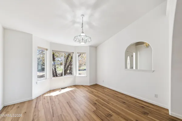 a view of an empty room with a window and wooden floor
