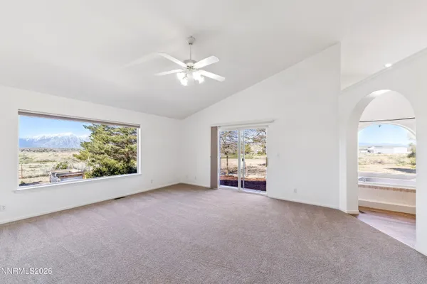 an empty room with windows and ceiling fan