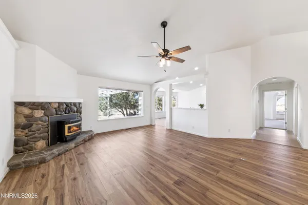 a view of an empty room with a fireplace and wooden floor