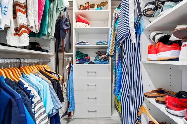 a view of walk in closet with clothes and shoes