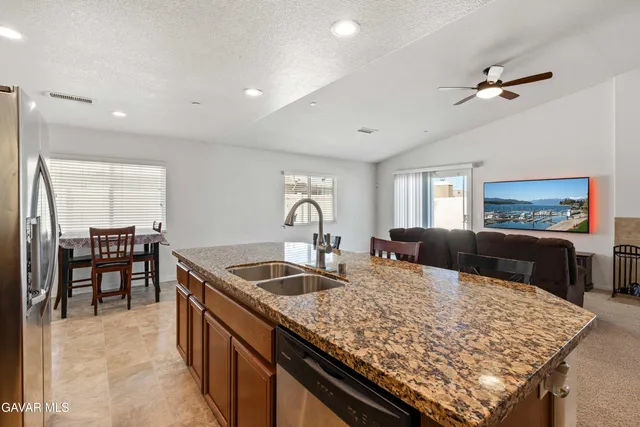 a kitchen with kitchen island granite countertop a table chairs sink and refrigerator