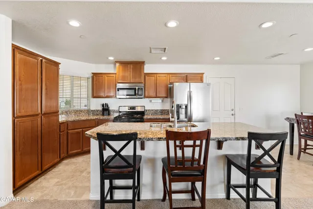 a kitchen with stainless steel appliances a table chairs refrigerator and cabinets
