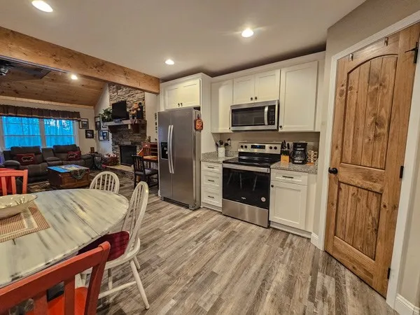 a kitchen with stainless steel appliances granite countertop a refrigerator a stove top oven a sink dishwasher and white cabinets with wooden floor