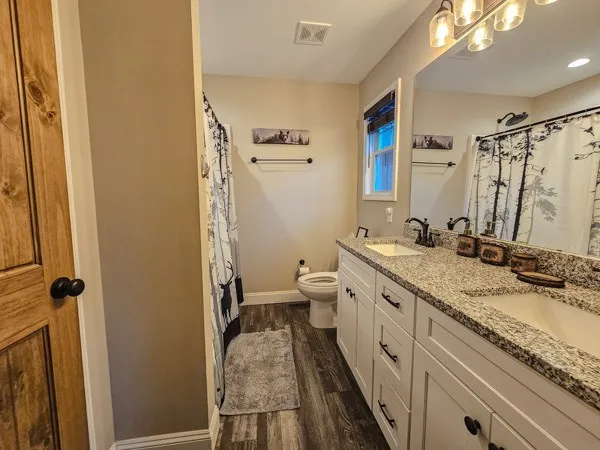 a bathroom with a granite countertop sink mirror vanity and toilet