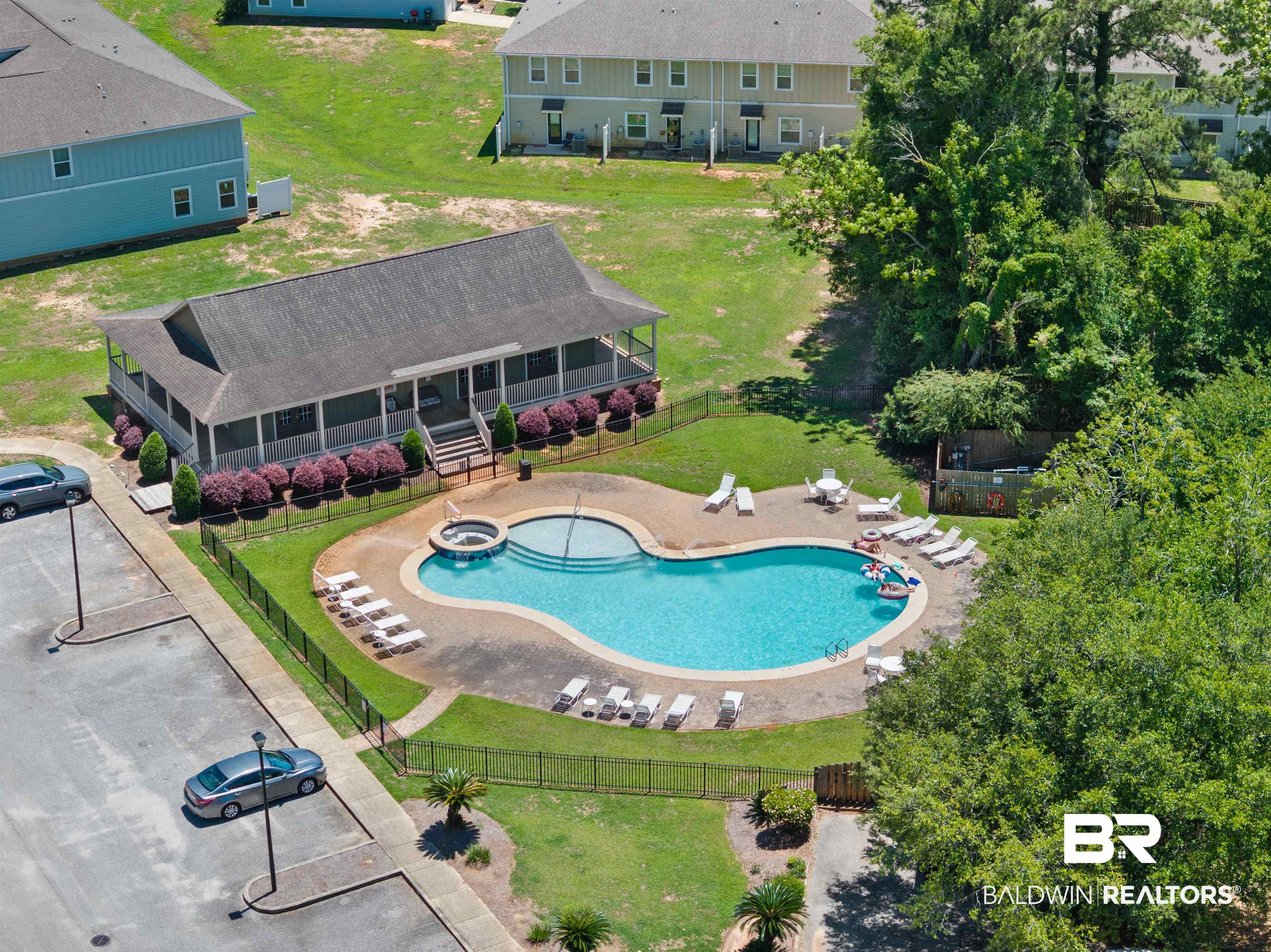 25806 Pollard Road, Unit 6 Daphne, AL 36526 - Photo 34 of 38 Resort-style pool area featuring a freeform swimming pool with integrated spa, surrounding lounge deck, and black perimeter fencing