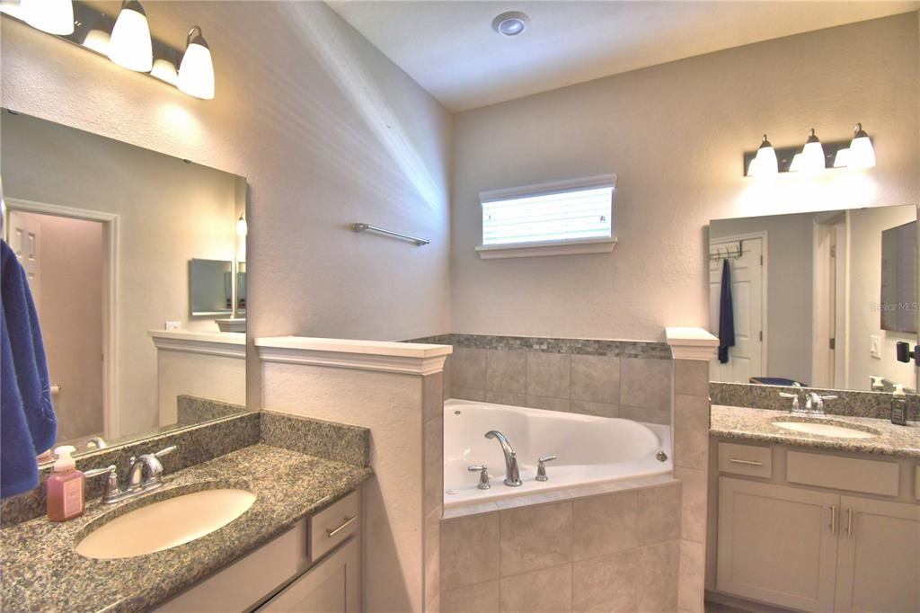 4340 Reding Way Lakeland, FL 33813 - Photo 45 of 63 a bathroom with a granite countertop sink a large mirror and a bathtub