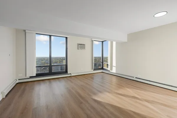 an empty room with wooden floor and windows