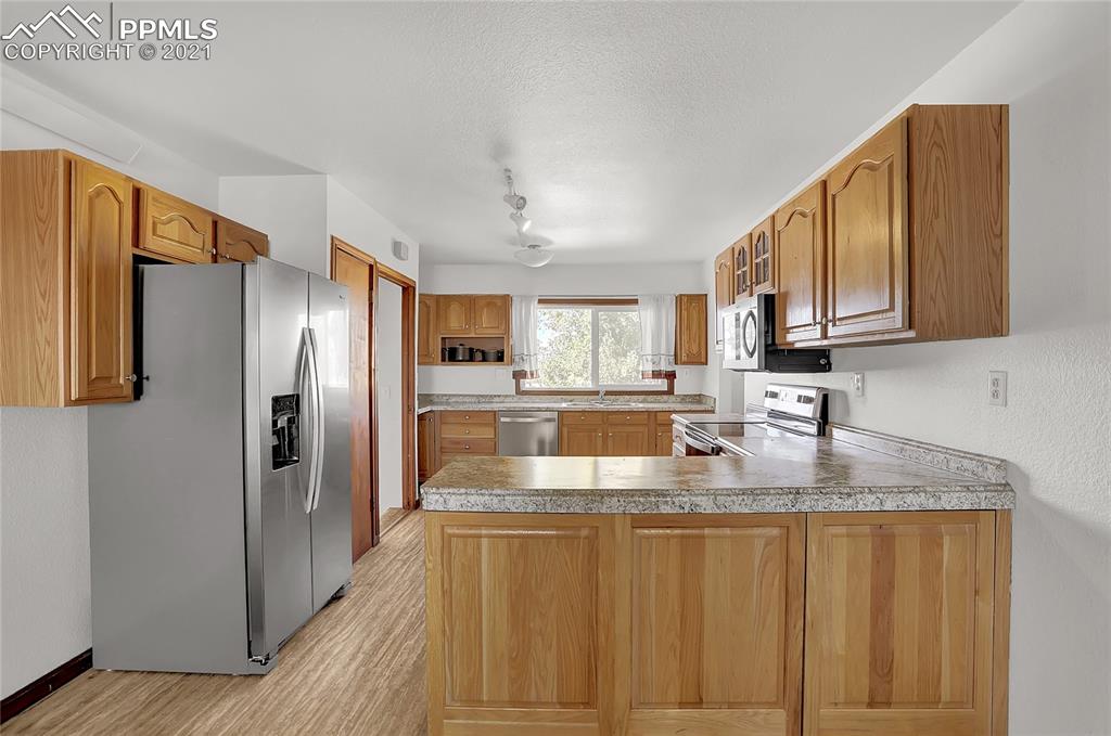 8155 North Log Road Peyton, CO 80831 - Photo 6 of 29 a kitchen with stainless steel appliances granite countertop a refrigerator a stove and a sink with wooden floor