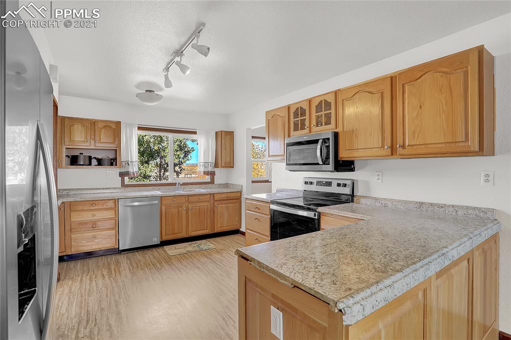 8155 North Log Road Peyton, CO 80831 - Photo 7 of 29 a kitchen with stainless steel appliances granite countertop a sink dishwasher stove and microwave with wooden floor