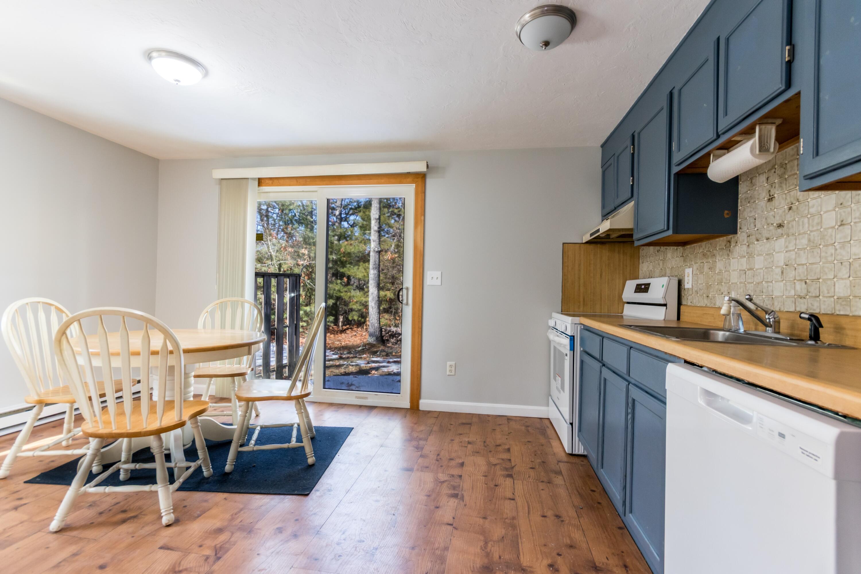 300 Falmouth Road, Unit 16A Mashpee, MA 02649 - Photo 11 of 25 a kitchen with stainless steel appliances granite countertop a stove top oven a sink a dining table and chairs with wooden floor