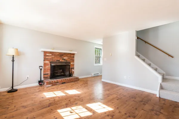 a view of empty room with fireplace and wooden floor