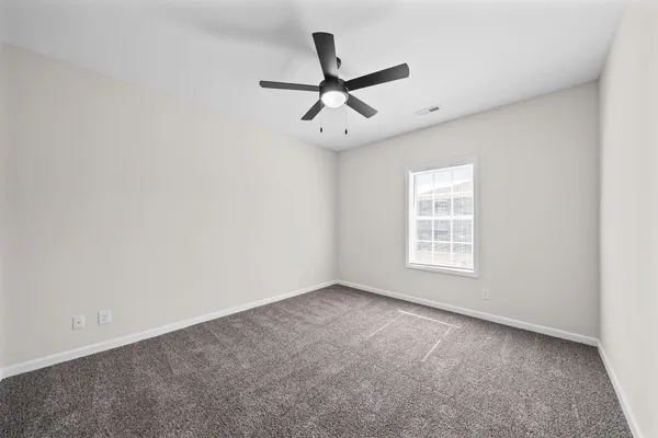 an empty room with ceiling fan and window