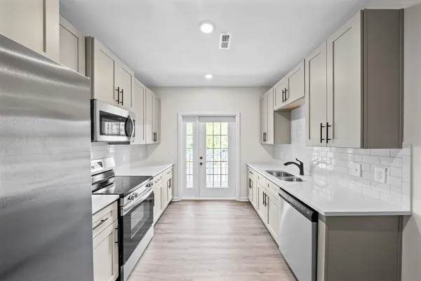 a large kitchen with stainless steel appliances lots of counter space and wooden floor
