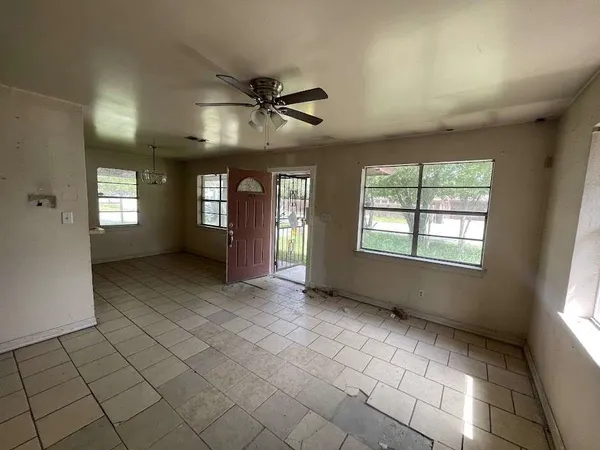 a view of an empty room with window and chandelier fan